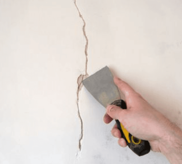 Filling a wall crack with a putty knife