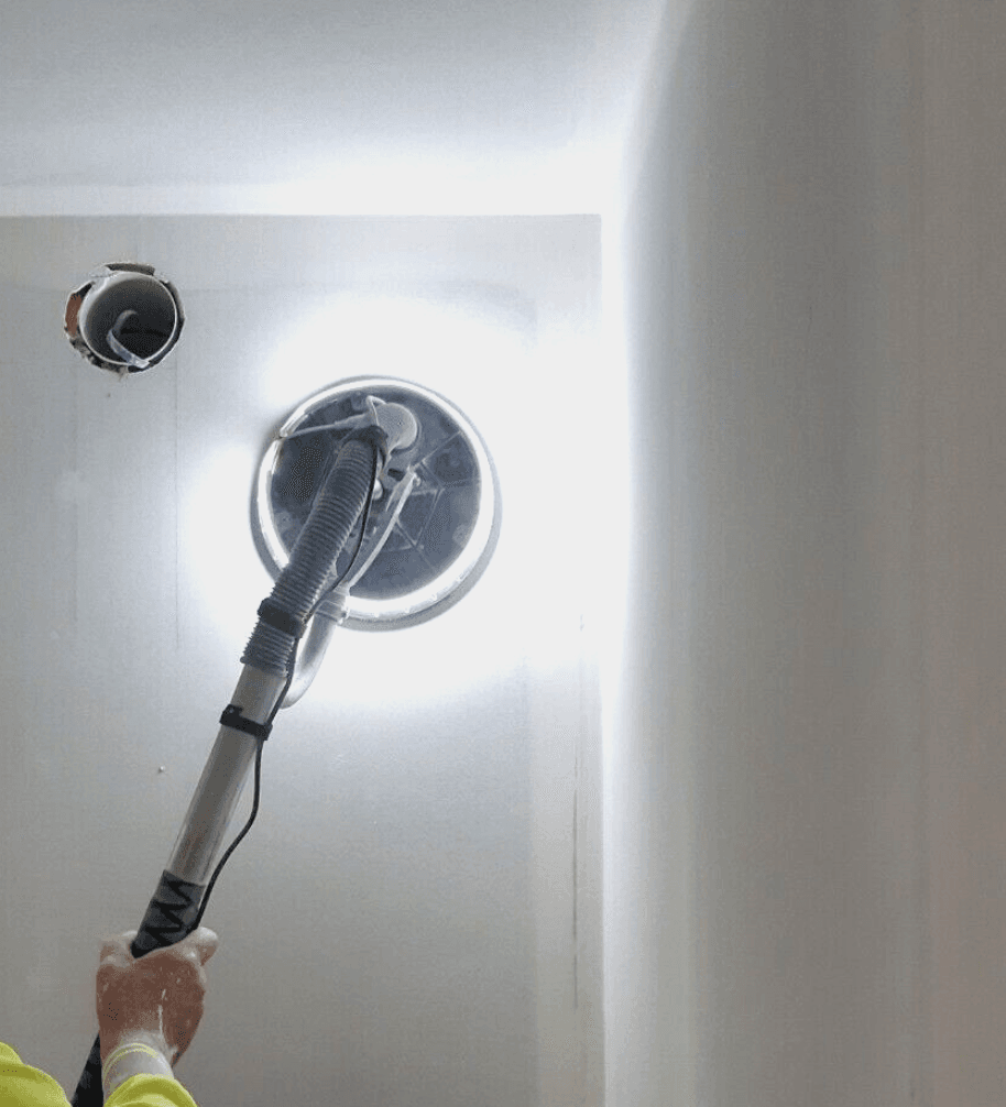 Sanding a drywall ceiling with a dust-control sander